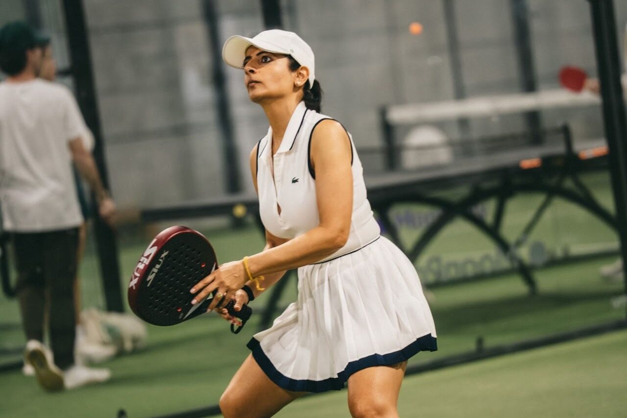 A member of Replay Club playing padel in an indoor court. 