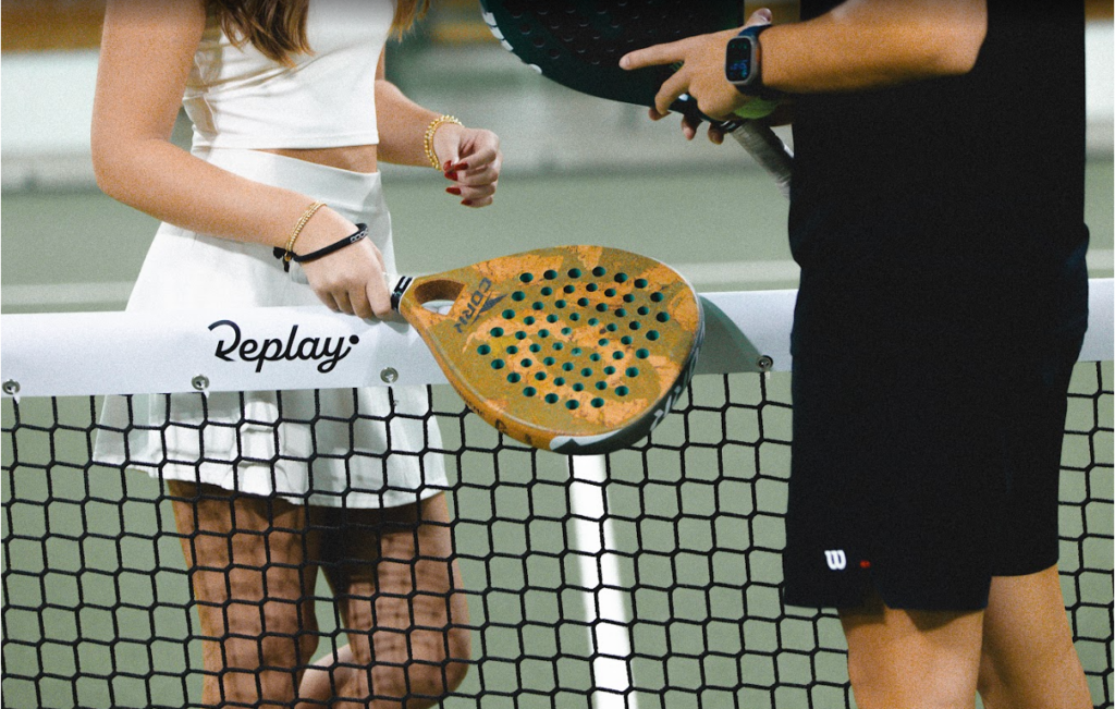 Two people chatting over the net in the Replay Club padel court