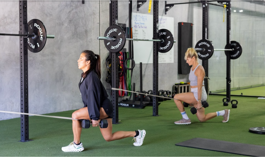 Two people exercising with dumbbells in a gym