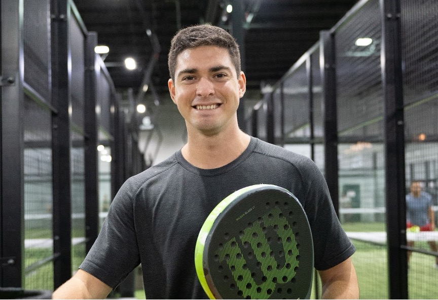 A Replay Club member smiling and holding a padel racquet