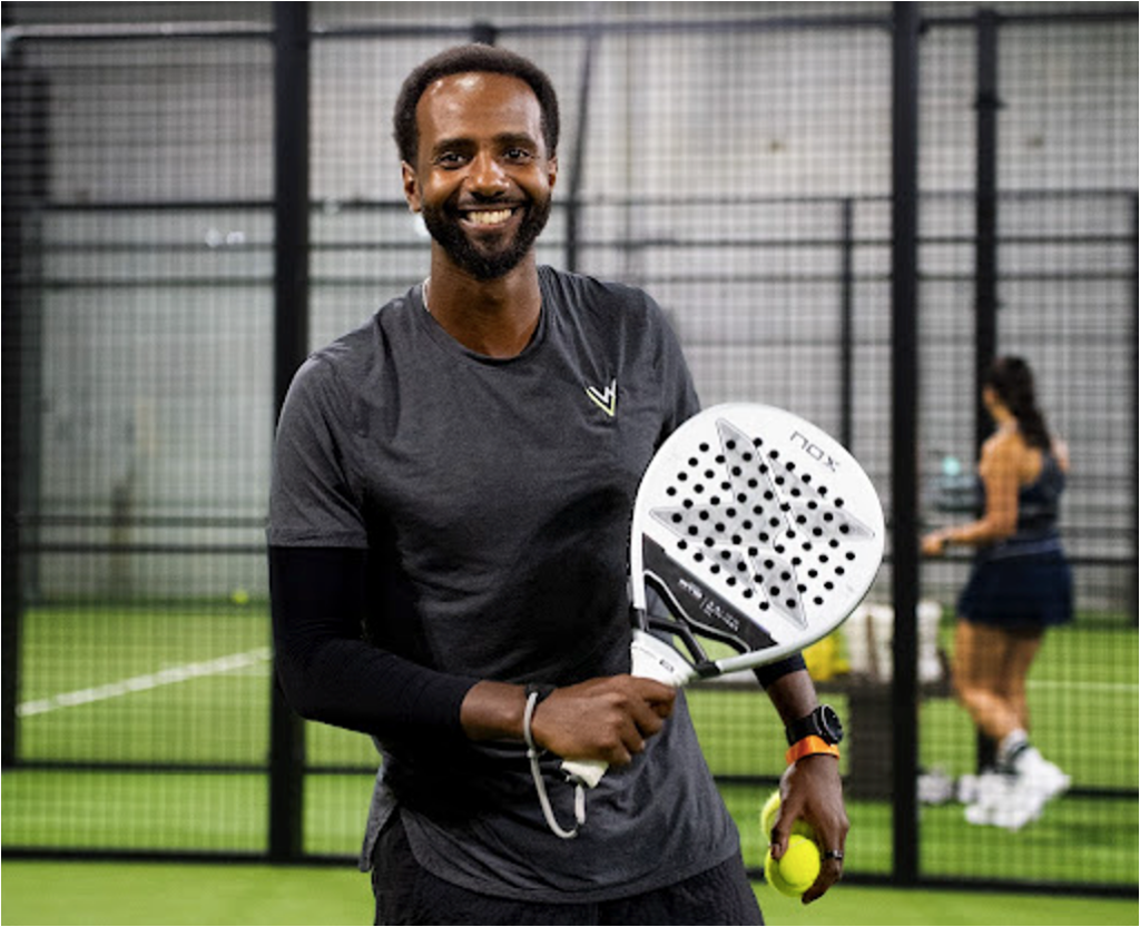 A man smiling and holding a padel racquet and a ball at Replay Club