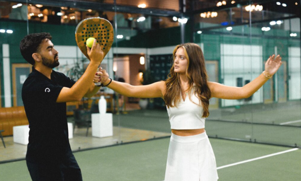 A padel coach teaching a player how to hold the ball at Replay Club