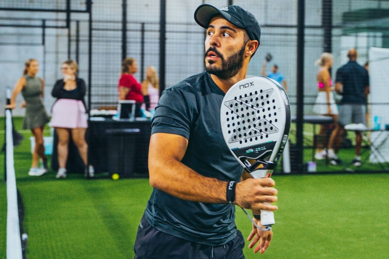 A member ofReplay Club holding a padel racquet in the middle of a match