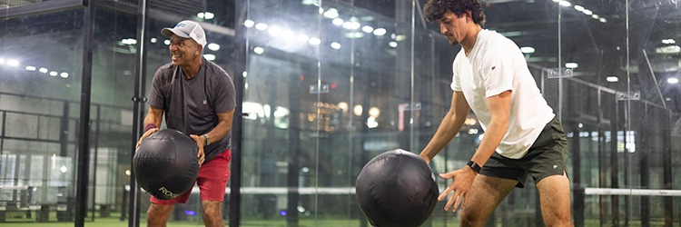 Two men doing medicine ball slams during a belly fat-burning workout at Replay Club gym