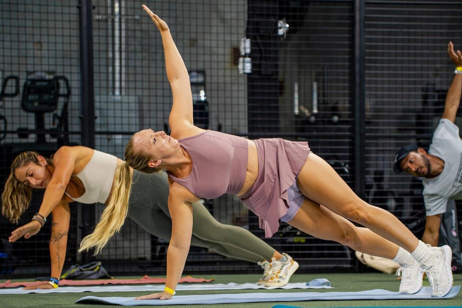 Members of Replay Club in a group fitness class on the 7,000 sq ft gym floor with strength training and turf workout zones.